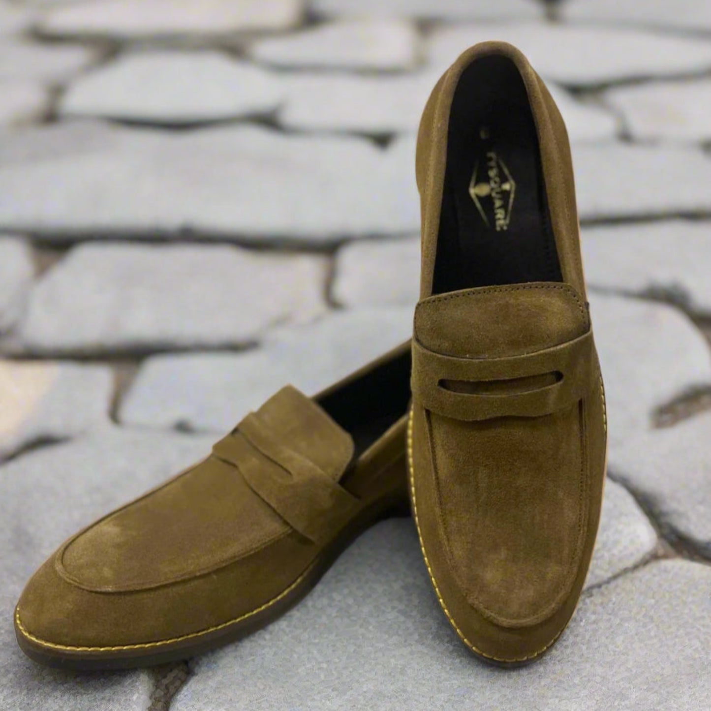 Pair of brown suede loafers on a light gray surface with a white background